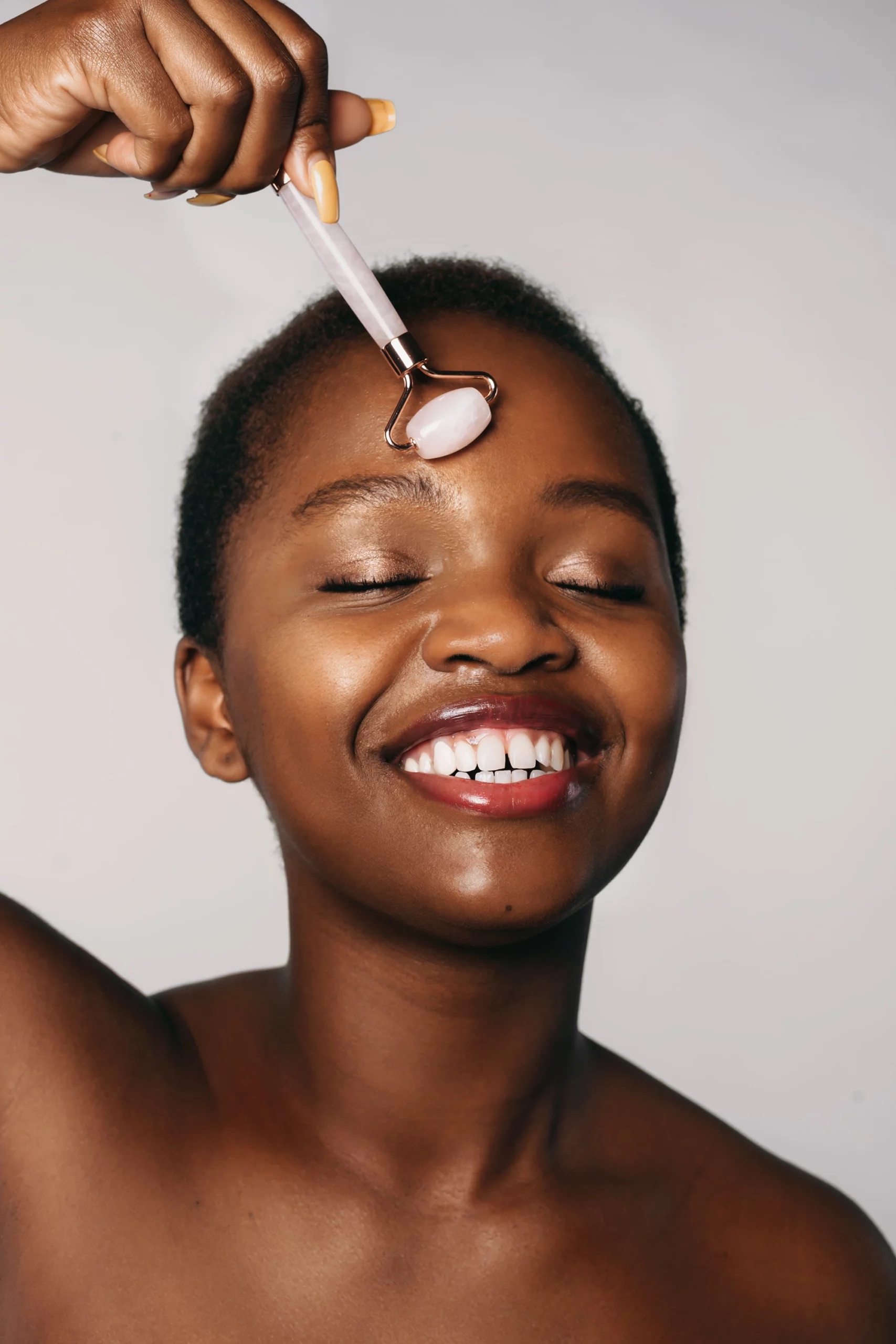 AdobeStock_479874163_1 Beautiful woman with closed eyes using jade roller on her face